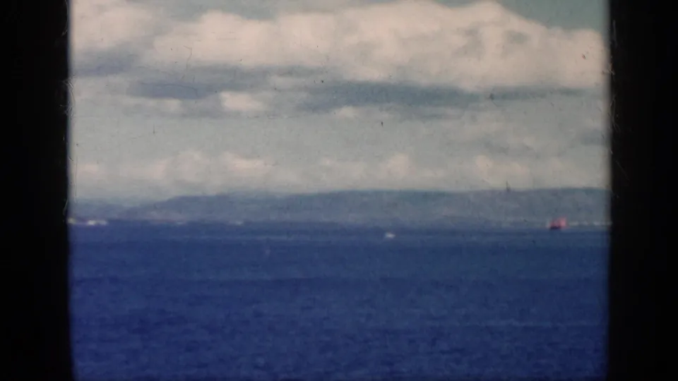 1962 Cuba 8mm frame showing blue water, a hazy coastal horizon, low clouds, and visible film-frame borders.