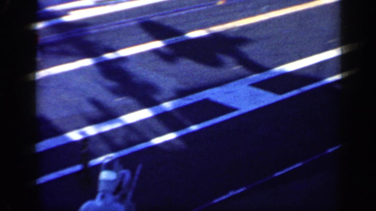 Obstructed high-angle view of an aircraft carrier deck with a jet nose and painted deck lines.