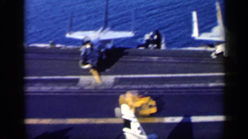 1962 catalog frame near Cuba showing aircraft on a U.S. carrier deck, possible deck personnel, equipment, and sea beyond.