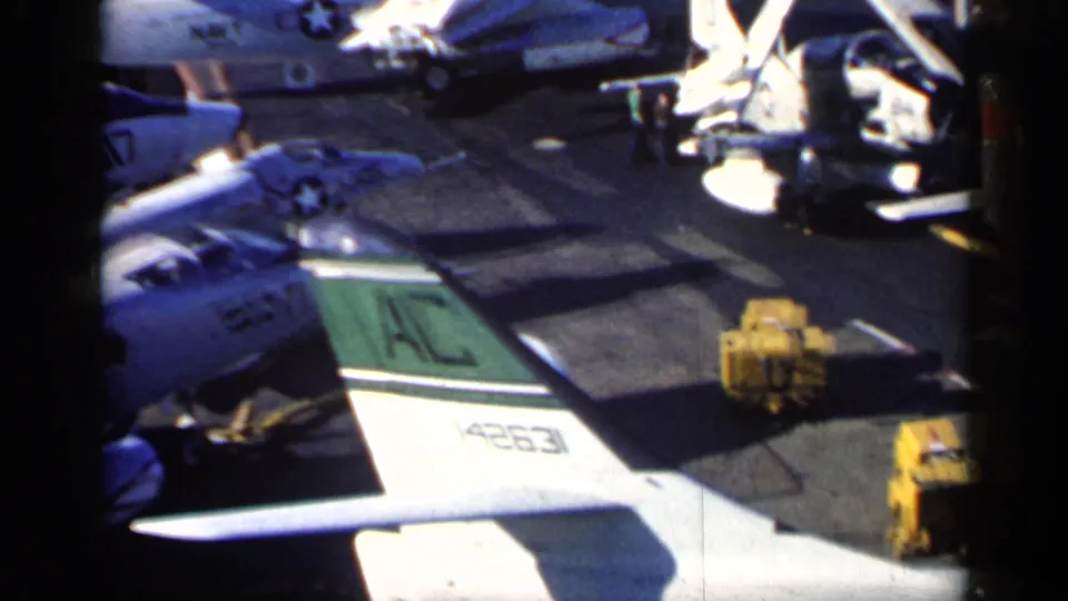 1962 Cuba-context carrier-deck frame showing a Navy jet tail marked 4263, yellow deck equipment, and nearby parked aircraft.