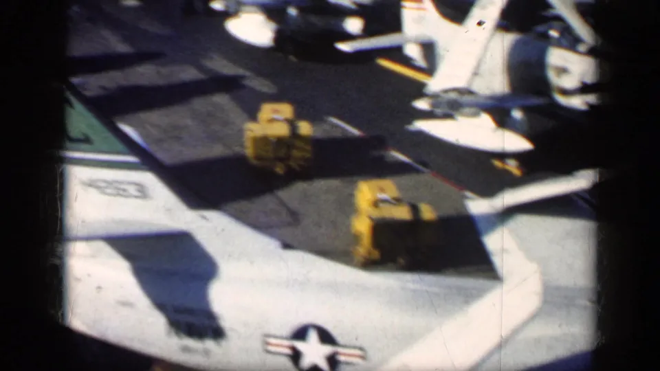 1962 8mm frame from supplied Cuba metadata showing U.S.-marked military aircraft parts, yellow equipment, and strong tarmac shadows.