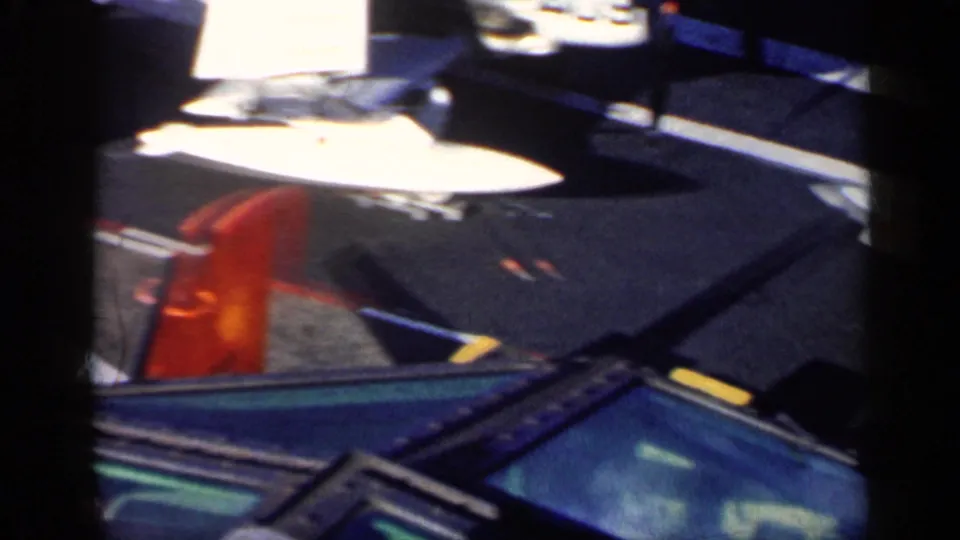 1962 8mm frame from supplied Cuba metadata showing overlapping parked aircraft sections, including a red-orange tail area and white wing surfaces.