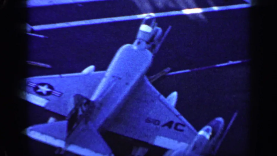 Overhead 8mm view of a U.S. military jet on a carrier deck, with wing insignia and strong blue color shift.