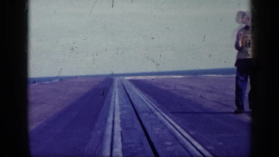 1962 Cuba airfield frame with a man near the film edge and runway lines receding toward a distant horizon.