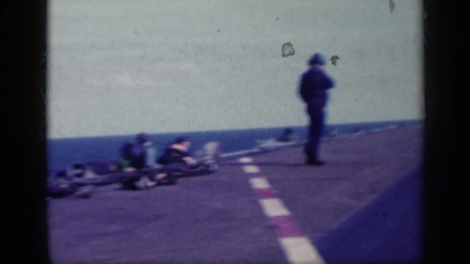 Cuba 1962 home-movie frame showing people on a coastal airfield, including a standing adult near painted runway markings.