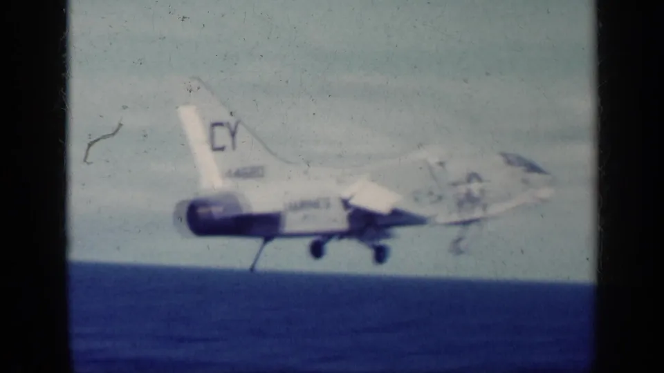 1962 Cuba-linked 8mm frame showing a military jet in side view just above the ocean, with visible tail markings and landing gear.