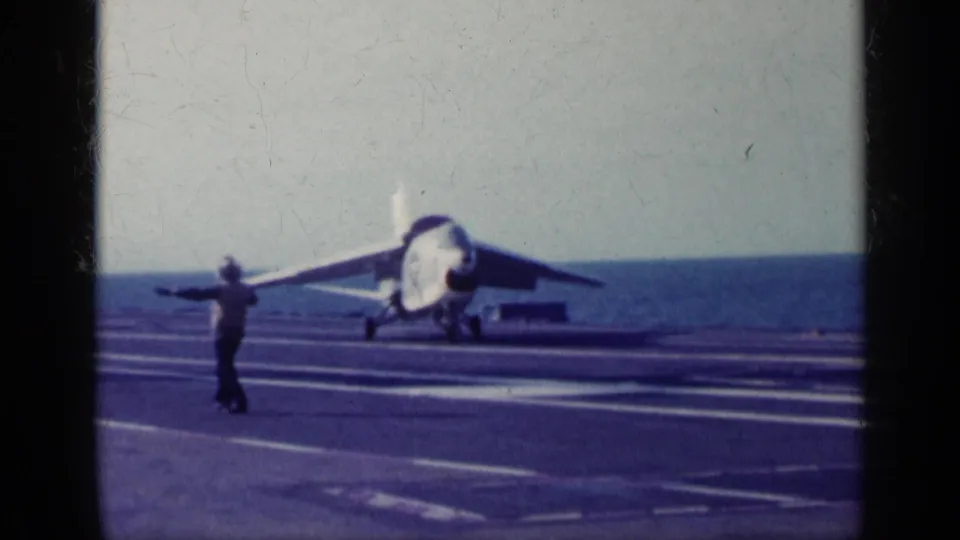 1962 Cuba-related 8mm frame of a jet turning or positioning on a carrier flight deck under guidance from a crew member.