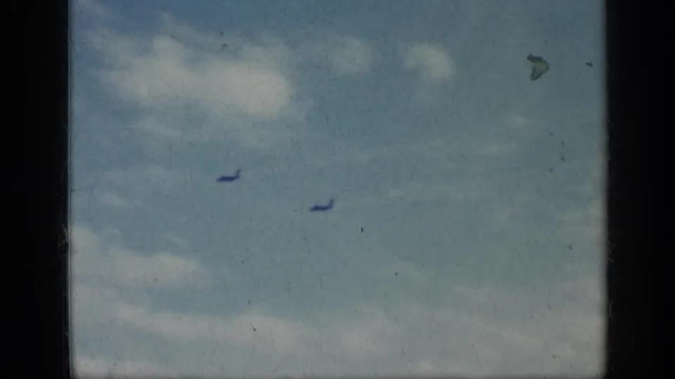 1962 Cuba-related 8mm frame showing two distant jets moving across a cloudy blue sky after the carrier-deck sequence.