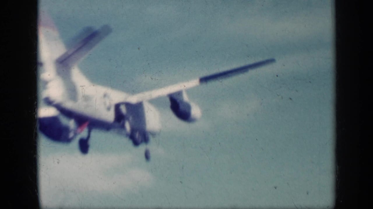 Twin-engine airliner with landing gear down seen close against a pale sky.