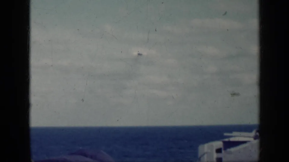 1962 Cuba home-movie frame showing sea and sky through a dark window or rail structure, with no people visible.