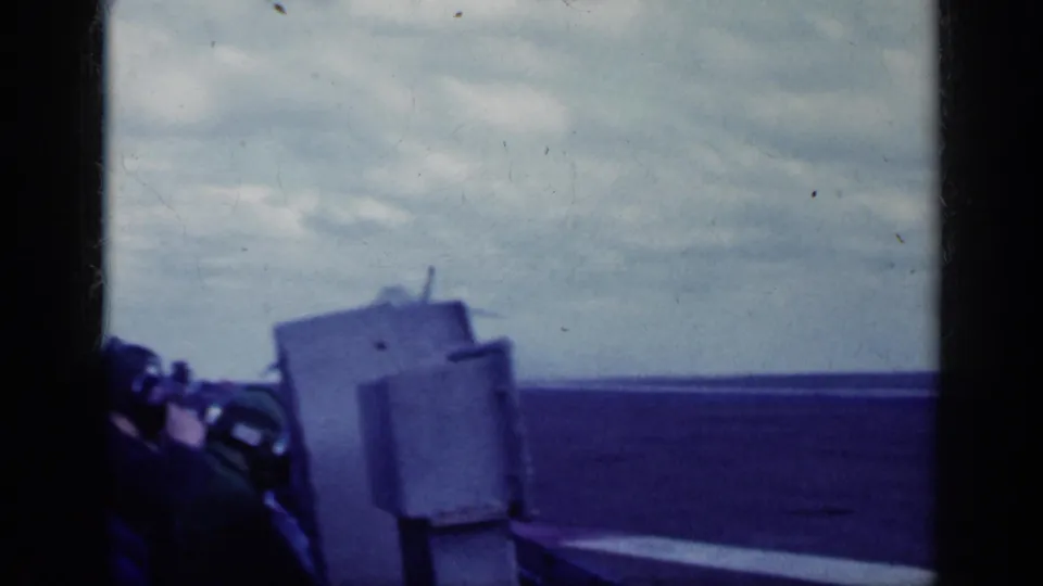 Helmeted personnel or pilots in headsets watch the aviation activity from deck level in 1962 Cuba-associated footage.