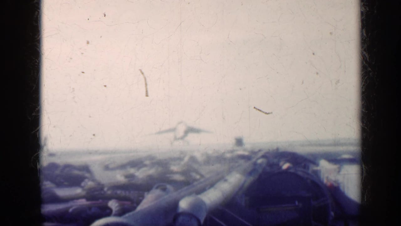 Aircraft carrier deck with aircraft and ocean horizon seen through 8mm frame edges.