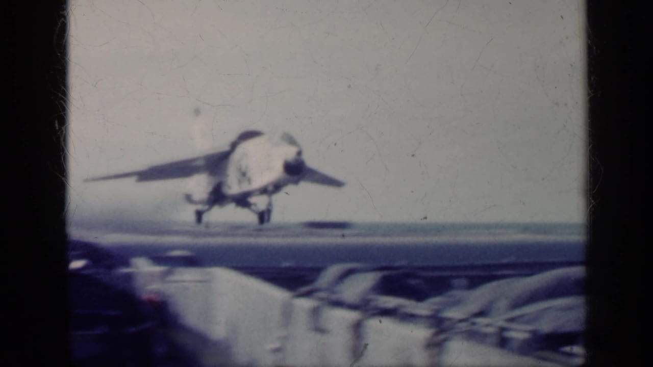 Jet aircraft lifting from an aircraft carrier deck over the ocean.