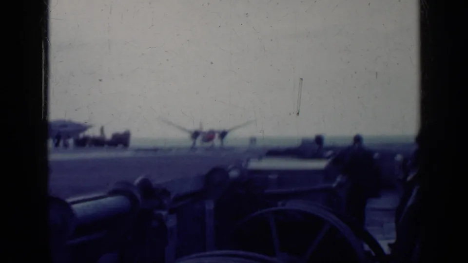 Cuba 1962 8mm frame showing a ship deck view with railings, distant people, and a small aircraft near the horizon.