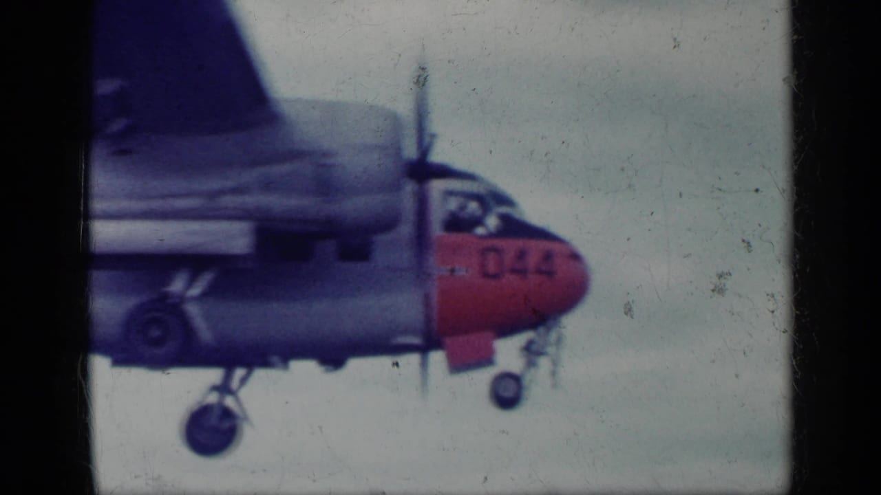 1962 Cuba archival frame showing a twin-engine military aircraft with red nose, visible propeller, and landing gear against a pale sky.