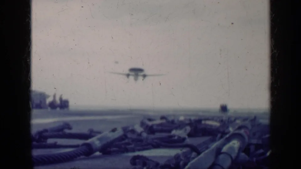 1962 Cuba archival frame showing the aircraft low over a runway or tarmac area, with hoses or equipment visible in the foreground.