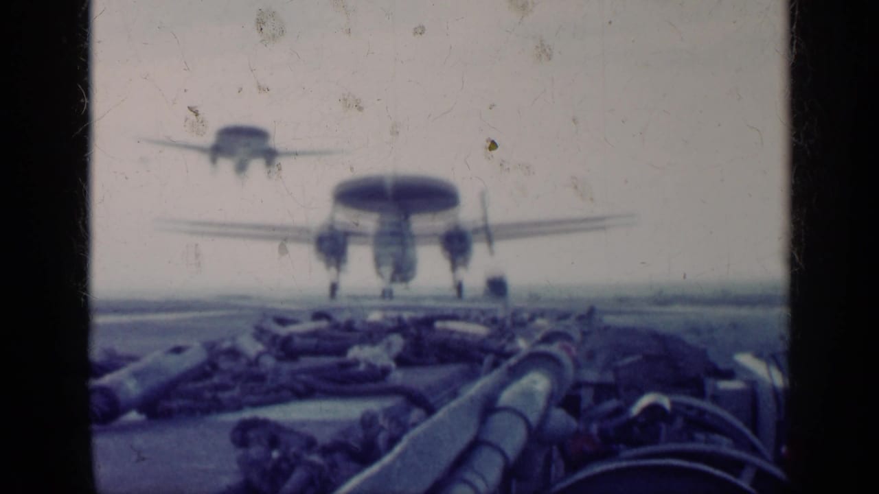 Radar aircraft approaches an aircraft carrier deck with another plane behind it.