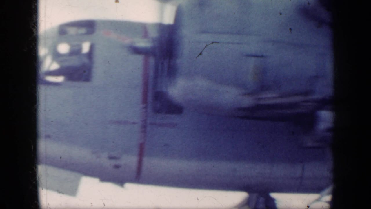 Close view of a military aircraft nose and propeller area seen through a dark film frame edge.