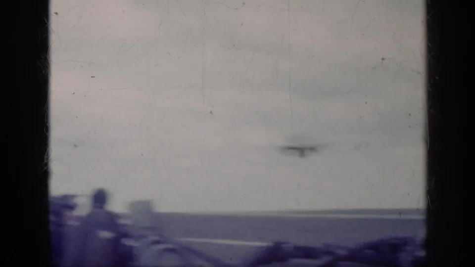 Soft, overexposed 8mm frame from the Cuba 1962 clip showing a carrier deck, horizon, and indistinct aircraft movement.