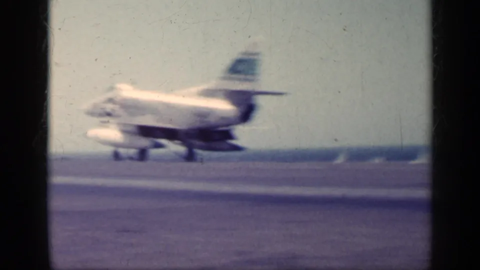 Final frame shows the U.S. Navy jet blurred in motion near the end of the carrier deck, with open water and horizon behind it.