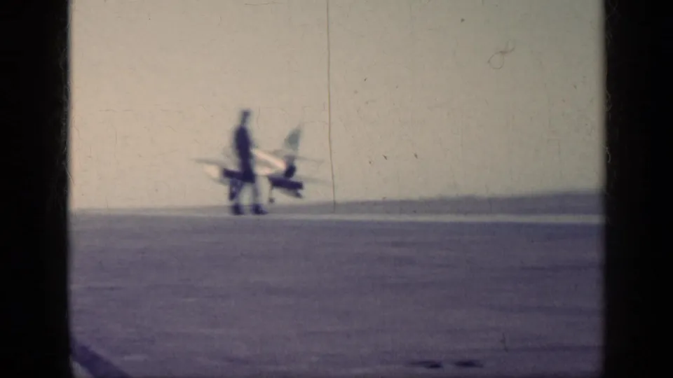 Distant 1962 carrier-deck view near Cuba showing a U.S. Navy jet and a person standing on the runway area.