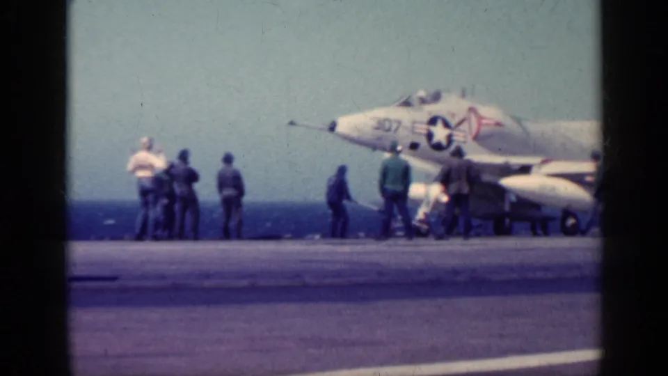 Several crew members stand around a U.S. Navy jet marked 307 on a carrier deck during the 1962 Cuba-labeled home movie clip.