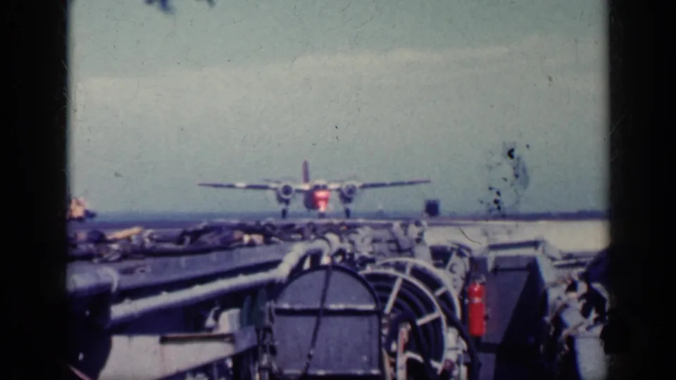 1962 Cuba 8mm frame of a military aircraft on or near an aircraft carrier deck, seen through home-movie film borders and faded color.