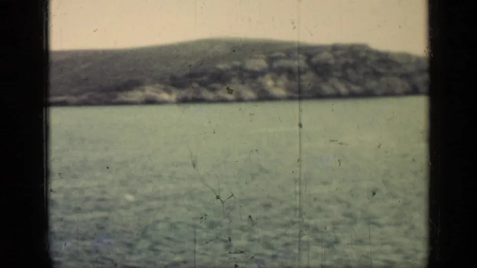 A soft 8mm view looks across open water toward a low coastline, consistent with the Cuba 1962 clip metadata.
