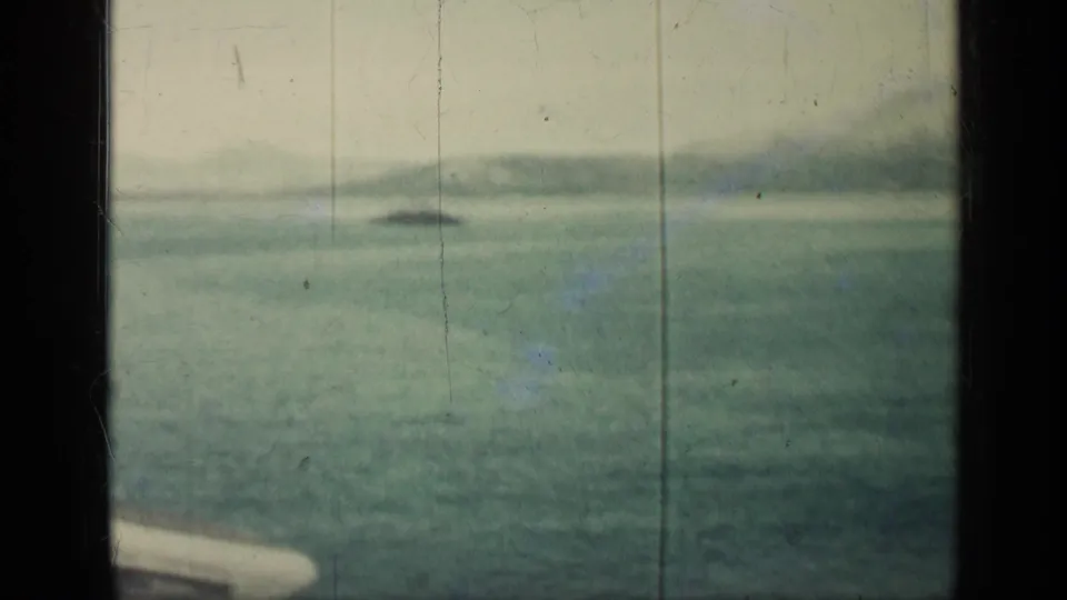 1962 Cuba seascape with a small dark boat on the horizon, low hazy hills, and a pale foreground edge from the vessel.