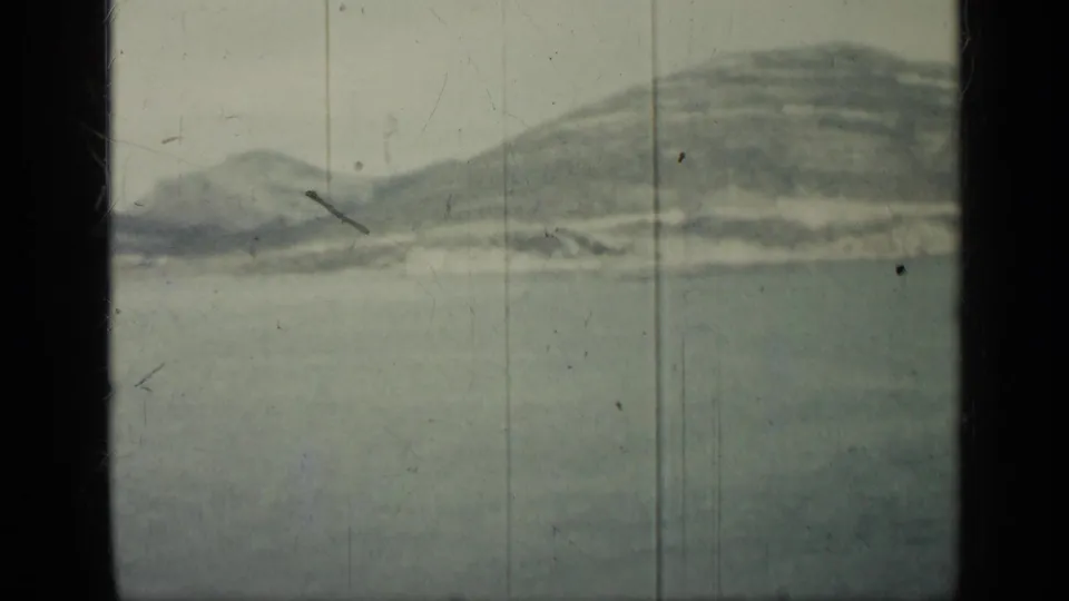 1962 Cuba 8mm frame showing calm water, distant hazy hills, pale sky, and visible film wear at the frame edges.