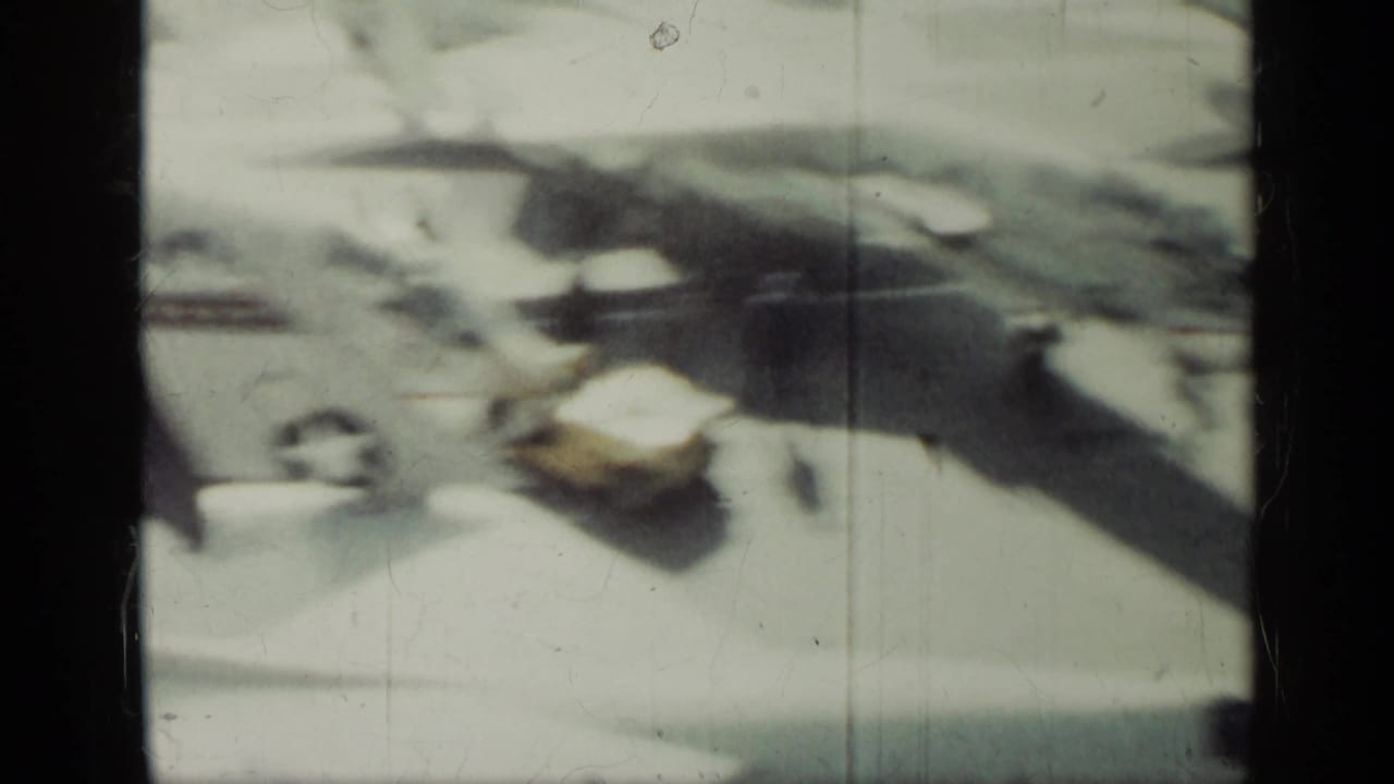 Soft 8mm frame from the Cuba 1962 clip showing a blurred high-angle view of aircraft shapes and people on a sunlit tarmac.