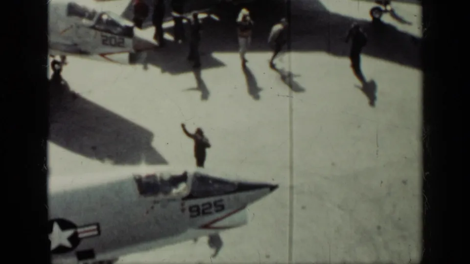 Cuba 1962 8mm frame with uniformed men and long shadows near U.S. Navy aircraft noses, including markings 925 and 202.