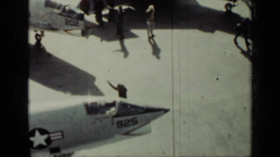 Final Cuba 1962 frame showing personnel crossing a sunlit tarmac near U.S. Navy fighter jets with visible 202 and 925 markings.