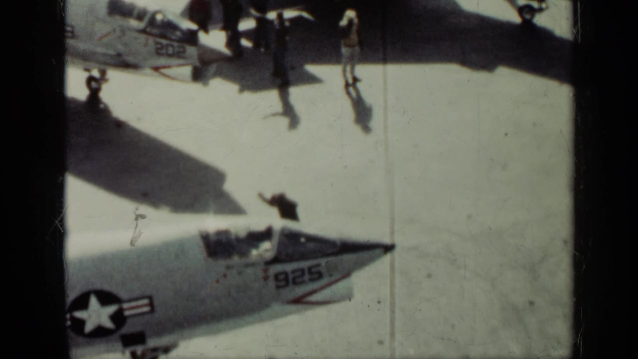 U.S. Navy jet noses and deck crew on an aircraft carrier deck.