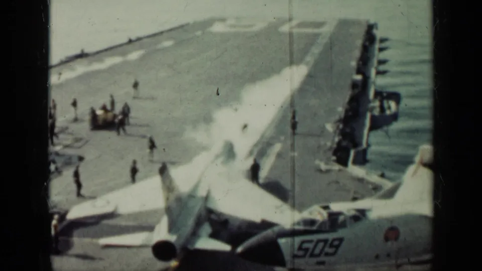 1962 Cuba-related carrier-deck view with U.S. Navy jets, aircraft marking 509, crew figures, and ocean beside the ship.