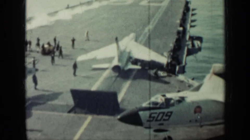 From an elevated 8mm viewpoint, crew activity surrounds a carrier jet, with the partial nose and number 509 of another aircraft visible below.
