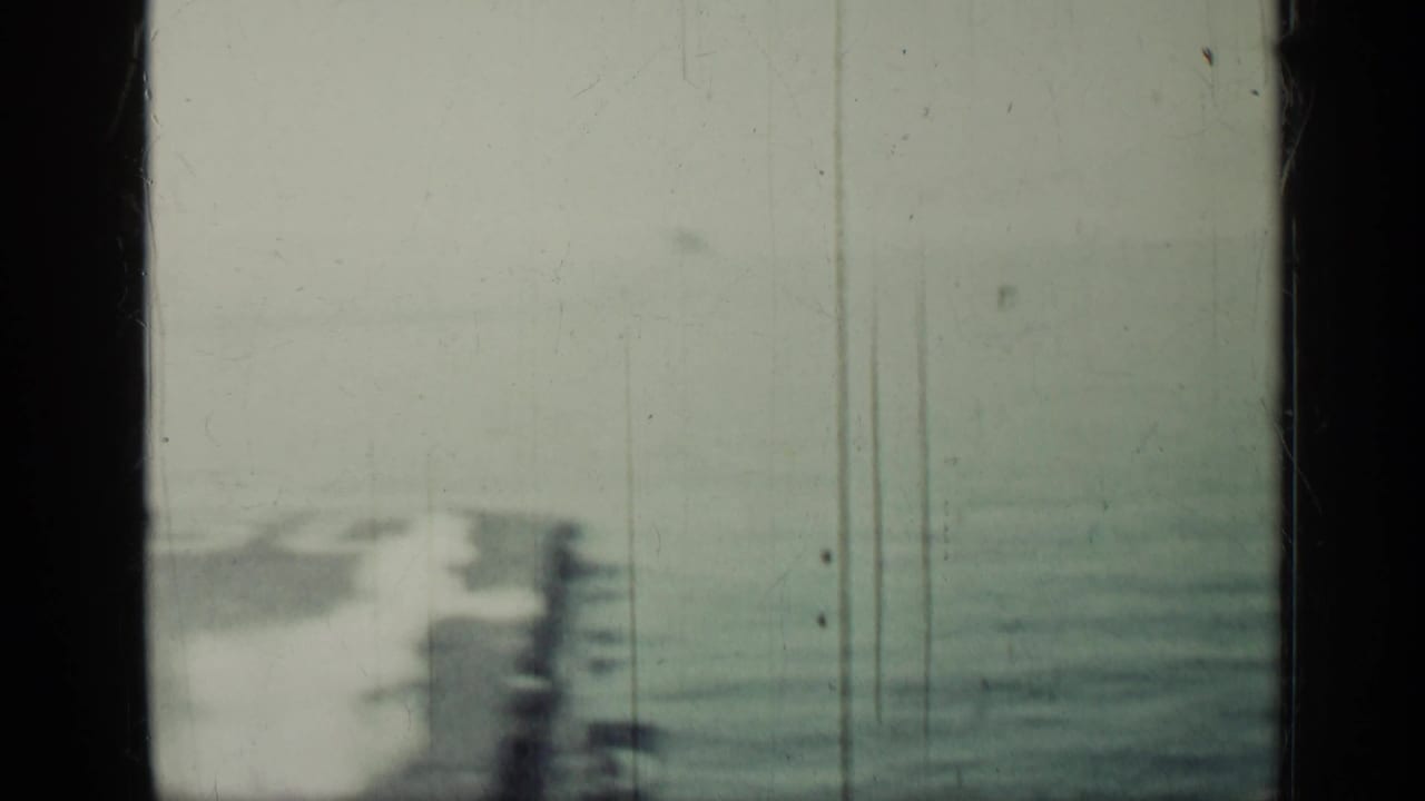 Blurred aircraft carrier deck and ocean seen through scratched 8mm film frames.