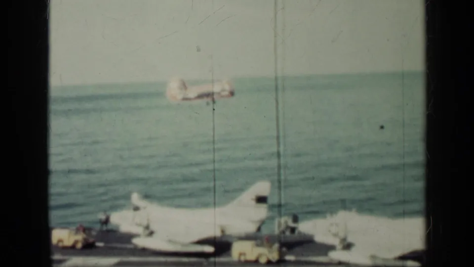 A propeller aircraft appears airborne over open water as carrier-deck aircraft and equipment remain visible below in the 1962 Cuba clip.