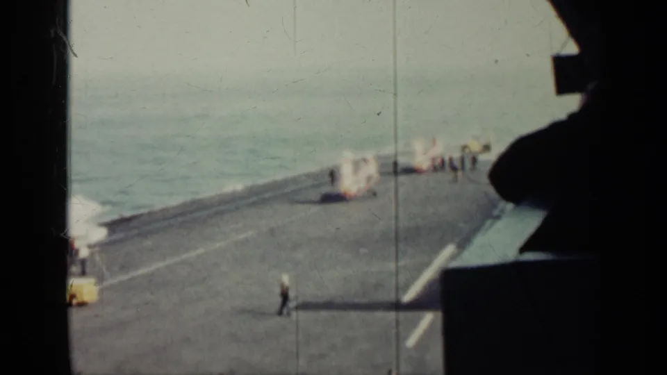 1962 Cuba-linked 8mm view of a military ship deck, with uniformed figures near equipment and a dark interior silhouette at right.