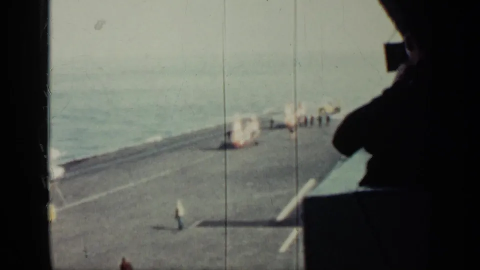 High-angle 8mm frame of the military ship deck in Cuba-linked 1962 footage, showing distant personnel and deck equipment.
