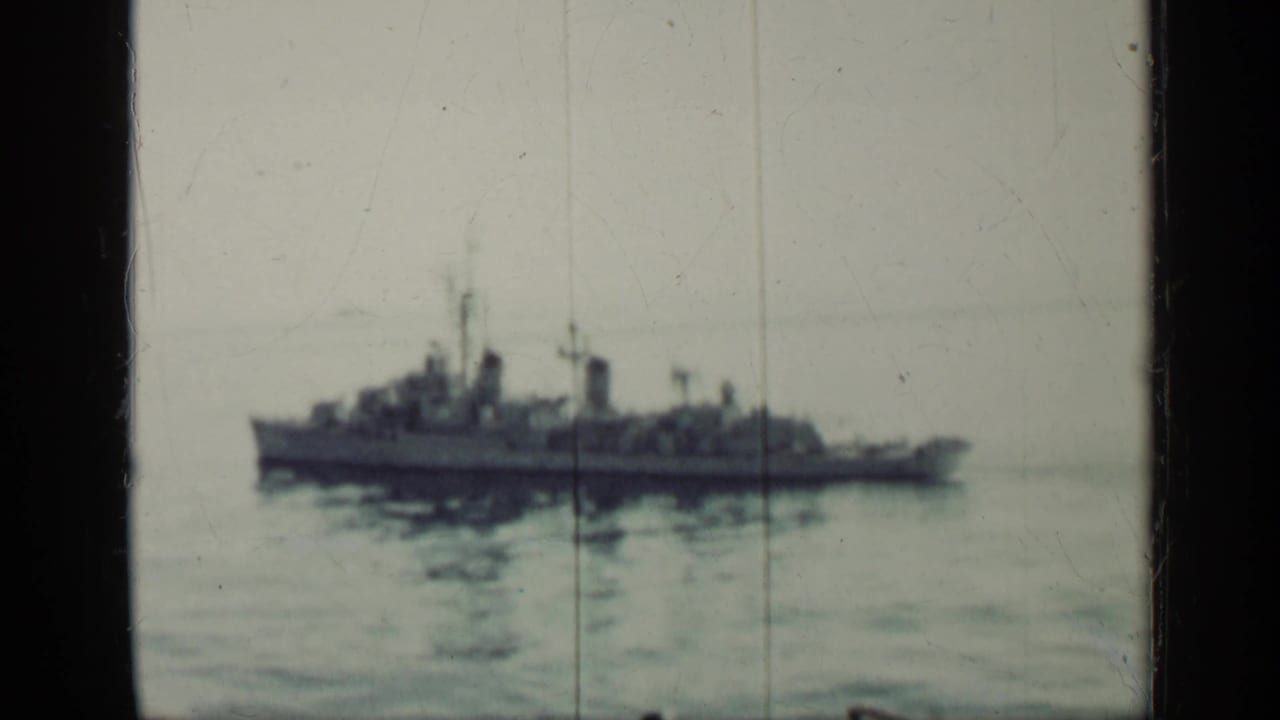 Distant naval ship on calm water seen through a dark optical border.