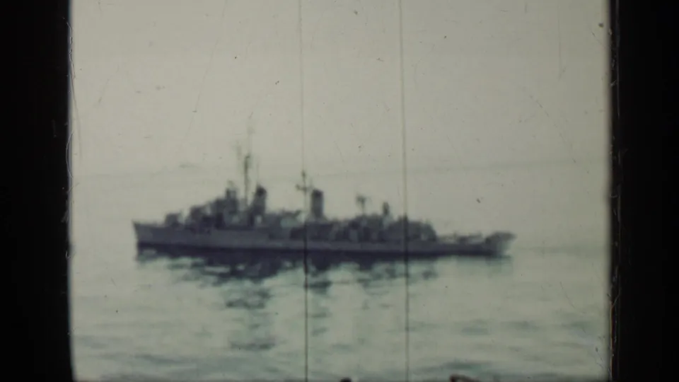 1962 Cuba-linked home-movie frame showing a distant naval ship on calm sea through a telescope-like view.