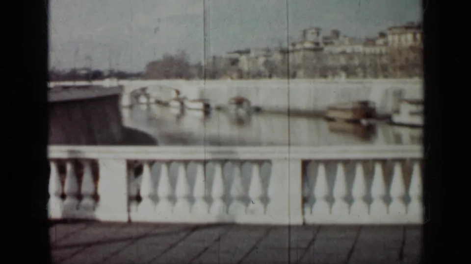 1962 Cuba frame showing a wider waterfront angle with a curving edge, white balustrade, moored boats, and distant city buildings.
