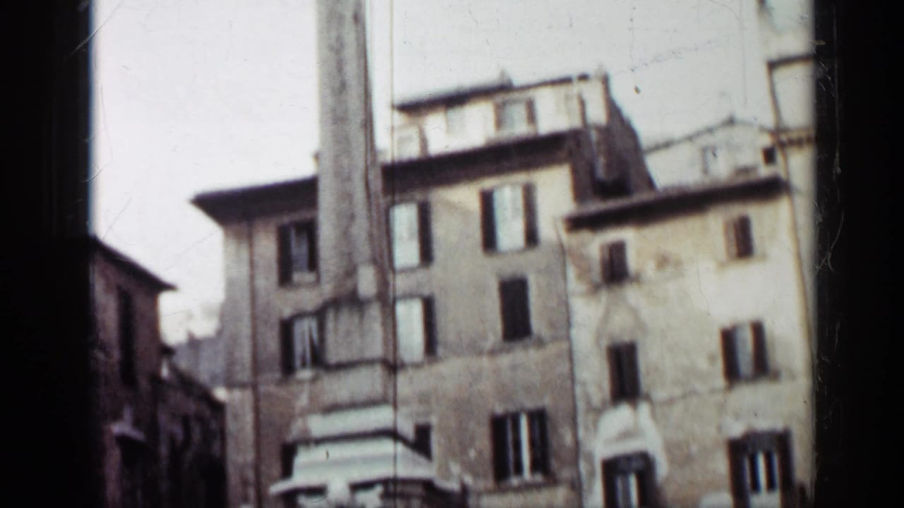 Low-angle view of a tall concrete monument beside weathered multi-story buildings.