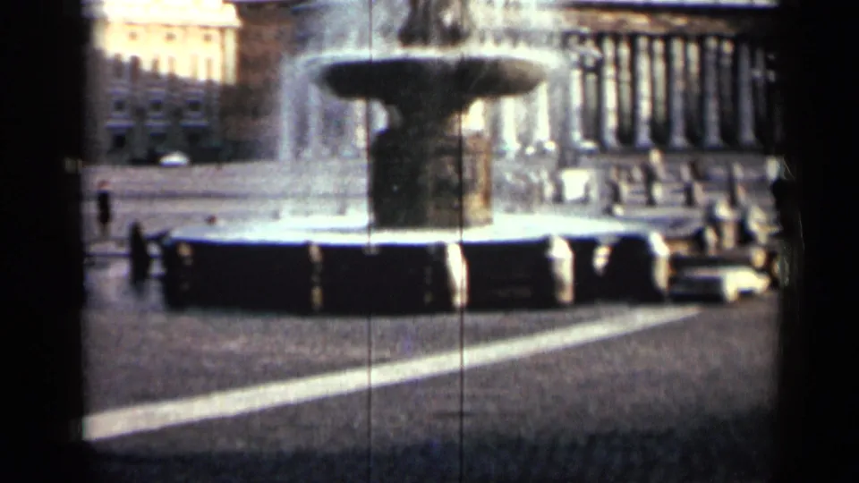 1962 Cuba city frame with a fountain in the foreground, columned landmark building behind it, open paving, and a car nearby.