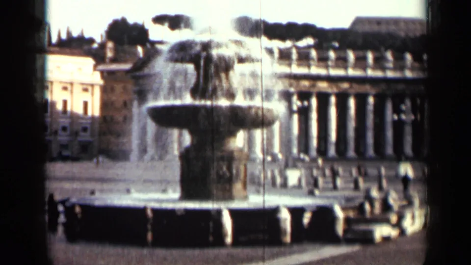 1962 Cuba 8mm frame with the fountain closer in view, backed by public buildings, columns, and dark tree shapes.