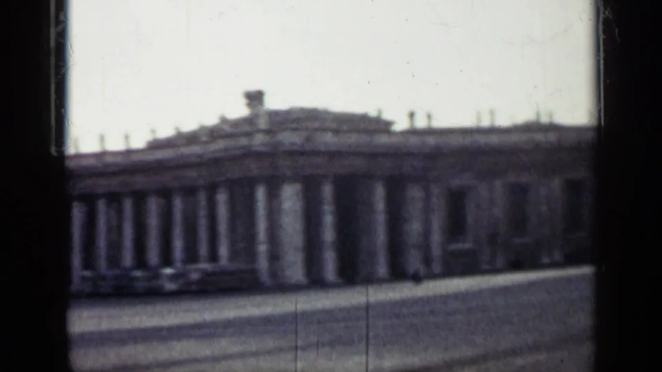 1962 Cuba 8mm frame of a long classical colonnade across an open public square, with soft focus and dark gate-edge framing.