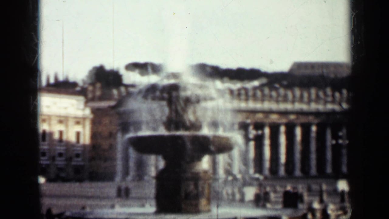 Fountain in front of a columned building and surrounding city architecture.