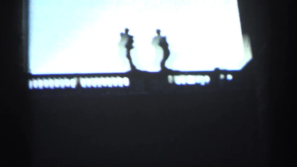 1962 Cuba 8mm frame with silhouetted statues along a balustrade, filmed against an overexposed bright sky.