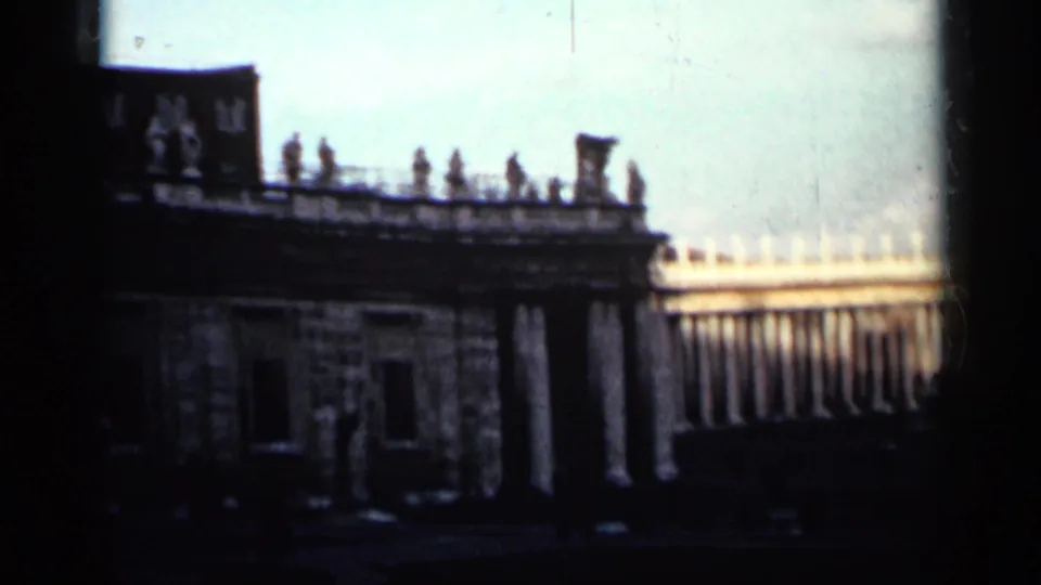 1962 Cuba 8mm frame with rooftop statues, a stone facade and part of a distant colonnaded palace complex.